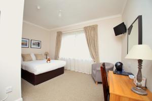 a bedroom with a bed and a desk with a desk at Loch Ness Guest House in Fort Augustus