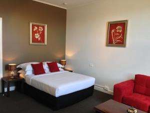 ein Hotelzimmer mit einem Bett und einem roten Stuhl in der Unterkunft Centennial Inn on Bathurst in Launceston