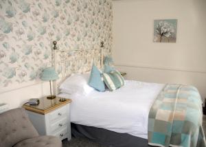 a bedroom with a white bed and a chair at Douglas House in Castle Douglas