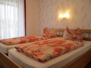 a bedroom with two beds with red and white covers at Pension Erika in Mehlmeisel
