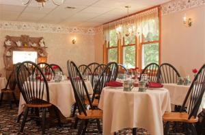 a dining room with tables and chairs with white table cloth at Inn at Ellis River in Jackson
