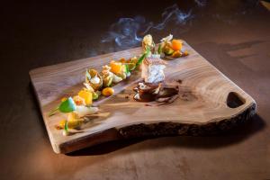 a wooden cutting board with fruit on a table at Hotel Waltershof in Ultimo