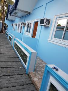 a blue building with white windows and a sidewalk at EDUARDO'S RESORT in Calapan