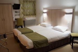 a hotel room with a bed, desk, lamp, and bedspread at Mont Vernon in Saint-Marcel