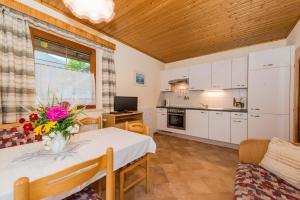 eine Küche und ein Esszimmer mit einem Tisch mit Blumen darauf in der Unterkunft Ferienwohnung Plozner in Rattendorf
