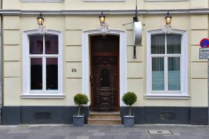 una casa con una puerta marrón y dos ventanas en Hotel Domstern, en Colonia