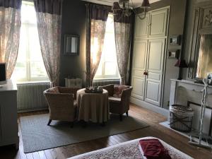 a living room with a table and chairs and windows at Le Clos des Hautes Loges in Les Loges