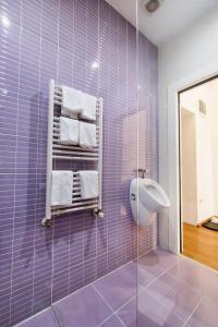 a purple tiled bathroom with a towel rack and a sink at Tia Apartments and Rooms in Zagreb