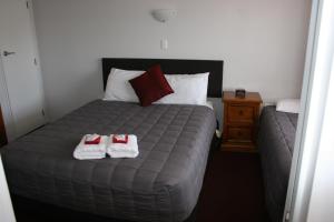 a bedroom with a bed with two towels on it at Burgundy Rose Motel in Whangarei