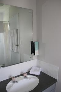 a bathroom with a sink and a large mirror at Burgundy Rose Motel in Whangarei
