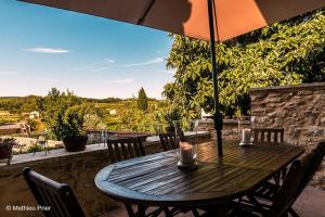 einen Holztisch mit Stühlen und einem Sonnenschirm auf einer Terrasse in der Unterkunft Clarberg - B&B in Saint-André-de-Roquepertuis