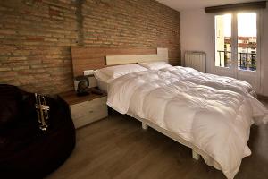 ログローニョにあるCasas Uva Plaza Mercado Logroñoのレンガの壁のベッドルーム1室(大型ベッド1台付)