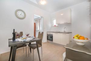 eine Küche und ein Esszimmer mit einem Tisch und einer Uhr in der Unterkunft Jakov in Postira