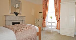 a bedroom with a bed and a fireplace and a window at Donnybrook Townhouse in Dublin