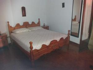 Cama de madera en un dormitorio con espejo en Appartamenti Bernardo I, en Roccella Ionica