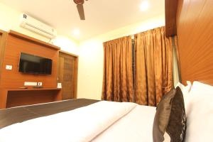 a hotel room with a bed and a television at The Grand Inn Mysore in Mysore