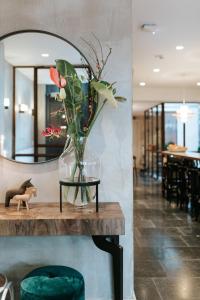 eine Vase mit Blumen auf einem Tisch vor einem Spiegel in der Unterkunft The Times Hotel in Amsterdam