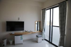 uma sala de estar com televisão e uma grande janela em Caibei Homestay em Magong