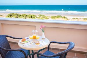 a table with two chairs and two glasses of orange juice at Hipotels Playa La Barrosa - Adults Only in Chiclana de la Frontera