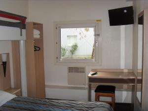 a bedroom with a bed and a desk and a window at Hôtel Class'eco in Courcouronnes