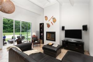 un soggiorno con divano e TV a schermo piatto di Madame Vacances Les Villas de Fontenelles a LʼAiguillon-sur-Vie