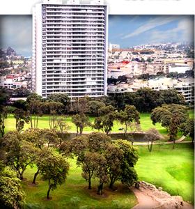 a park with trees in front of a tall building at Exclusive Apartment in Lima