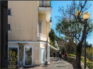 a white building with people walking on a street at Le Camerelle 83 in Capri