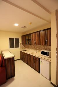 a kitchen with wooden cabinets and a microwave at شقق توليب الروضه للشقق المخدومة in Riyadh +22 photos