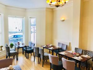 uma sala de jantar com mesas, cadeiras e janelas em The Westlynne Hotel & Apartments em Manchester