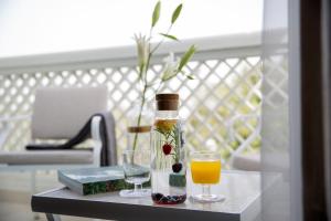 a table topped with a glass of orange juice and a vase filled with at Park Regis Boutique Hotel Jumeirah in Dubai