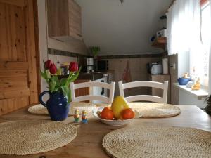 a wooden table with a bowl of fruit and flowers on it at Ferienwohnung Zum Alten Dorfkrug in Schlemmin