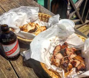 a table with two baskets of food and a bottle of beer at Artist Place Kensington 2BR New Kingston in New Kingston +11 photos