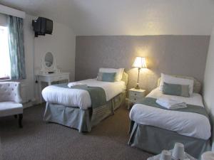 a hotel room with two beds and two nightstands at Holliers Hotel in Shanklin