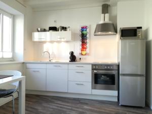 a kitchen with white cabinets and a stainless steel refrigerator at Zimmer zum Hof in Herdecke