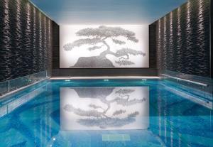 a swimming pool with a bonsai art on the wall at The Langham London in London