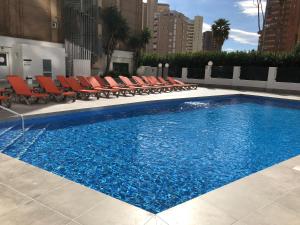 een groot zwembad met stoelen en een zonneklep bij Apartamentos Amalia By Mc in Benidorm