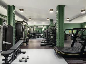 a gym with rows of tread machines and green walls at The Langham London in London