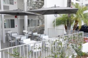 a balcony with tables and chairs and umbrellas at Pasadena Rose & Crown Hotel in Pasadena