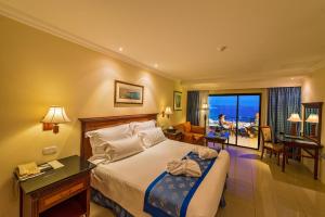 a hotel room with a bed and a view of the ocean at Grand Hotel Gozo in Għajnsielem