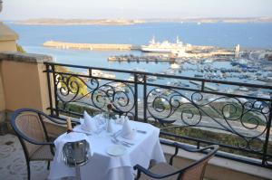a table on a balcony with a view of a harbor at Grand Hotel Gozo in Għajnsielem
