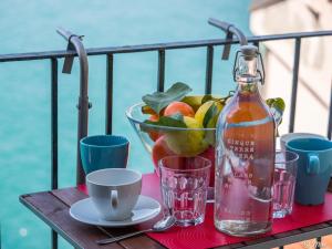 a table with a bottle of drink and a bowl of fruit at Il Baluardo Sea View Apartment on the Cliff in Manarola