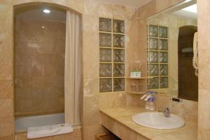 a bathroom with a sink and a tub and a mirror at Surabaya Suites Hotel Powered by Archipelago in Surabaya