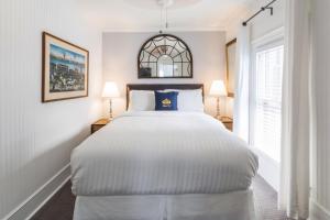 Un dormitorio con una gran cama blanca y una ventana en Queen Vic Guest House en Provincetown
