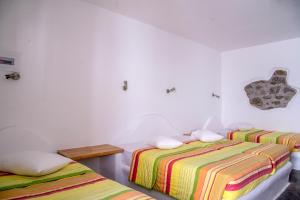 two beds in a room with white walls at Paradise Beach Resort in Paradise Beach