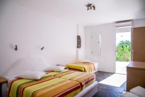 two beds in a white room with a window at Paradise Beach Resort in Paradise Beach