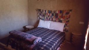 Dormitorio pequeño con cama con colcha a cuadros en Secret du Sahara, en Merzouga