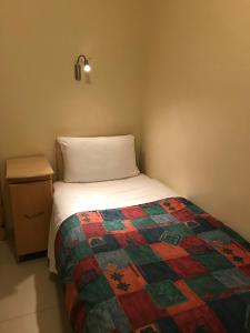 Seven Dials Hotel في لندن: غرفة نوم صغيرة مع سرير وموقف ليلي