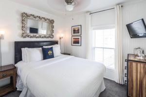 a white bedroom with a large bed and a window at Queen Vic Guest House in Provincetown