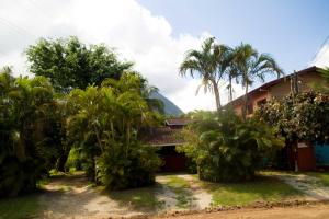 a resort with palm trees in front of a building at Chalés Mariah in Ubatuba