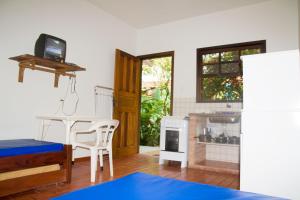 a living room with a table and a kitchen at Chalés Mariah in Ubatuba